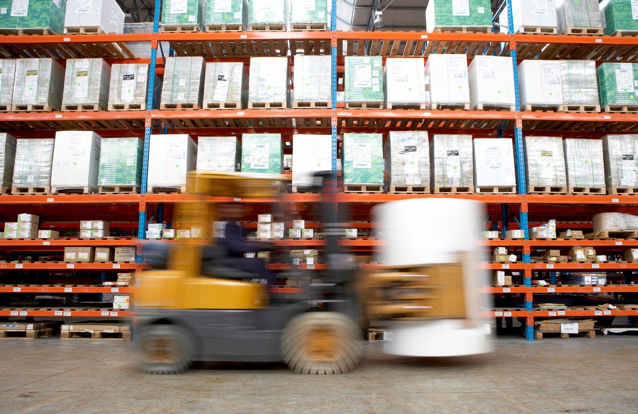 Single forklift moving fast across a warehouse floor