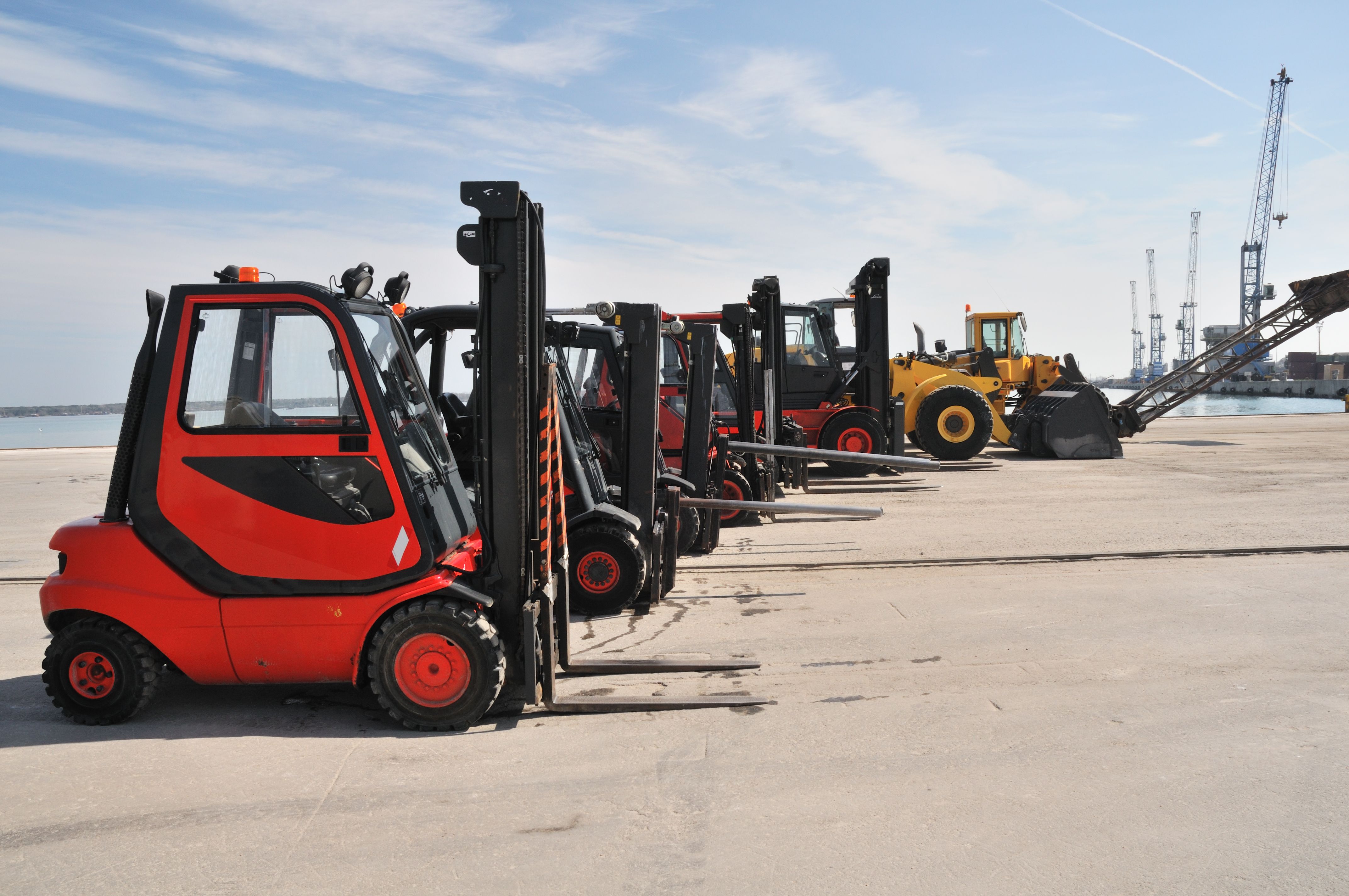 A fleet of forklift lined up outside.