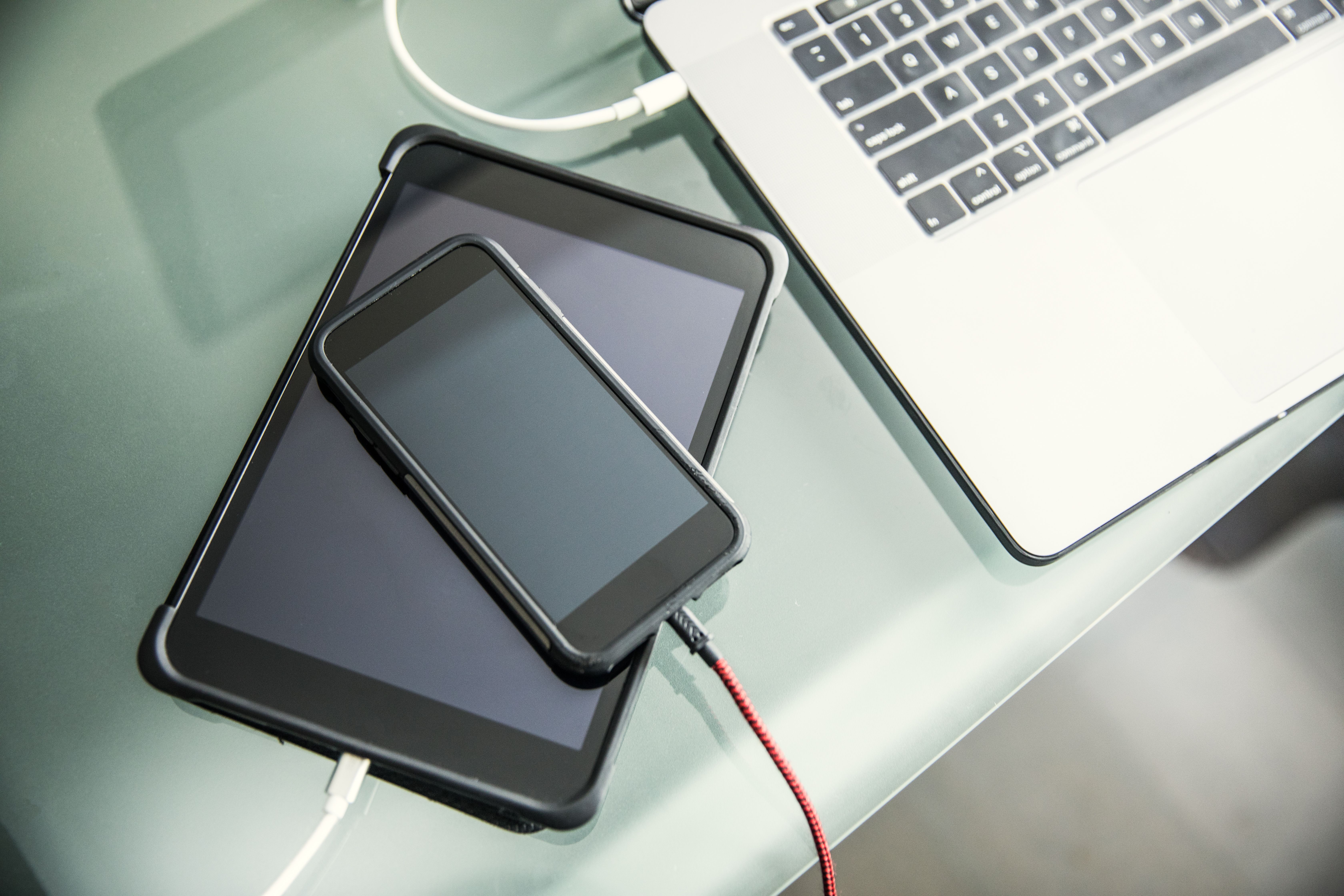An smartphone and a tablet sitting on top of one another on a desk
