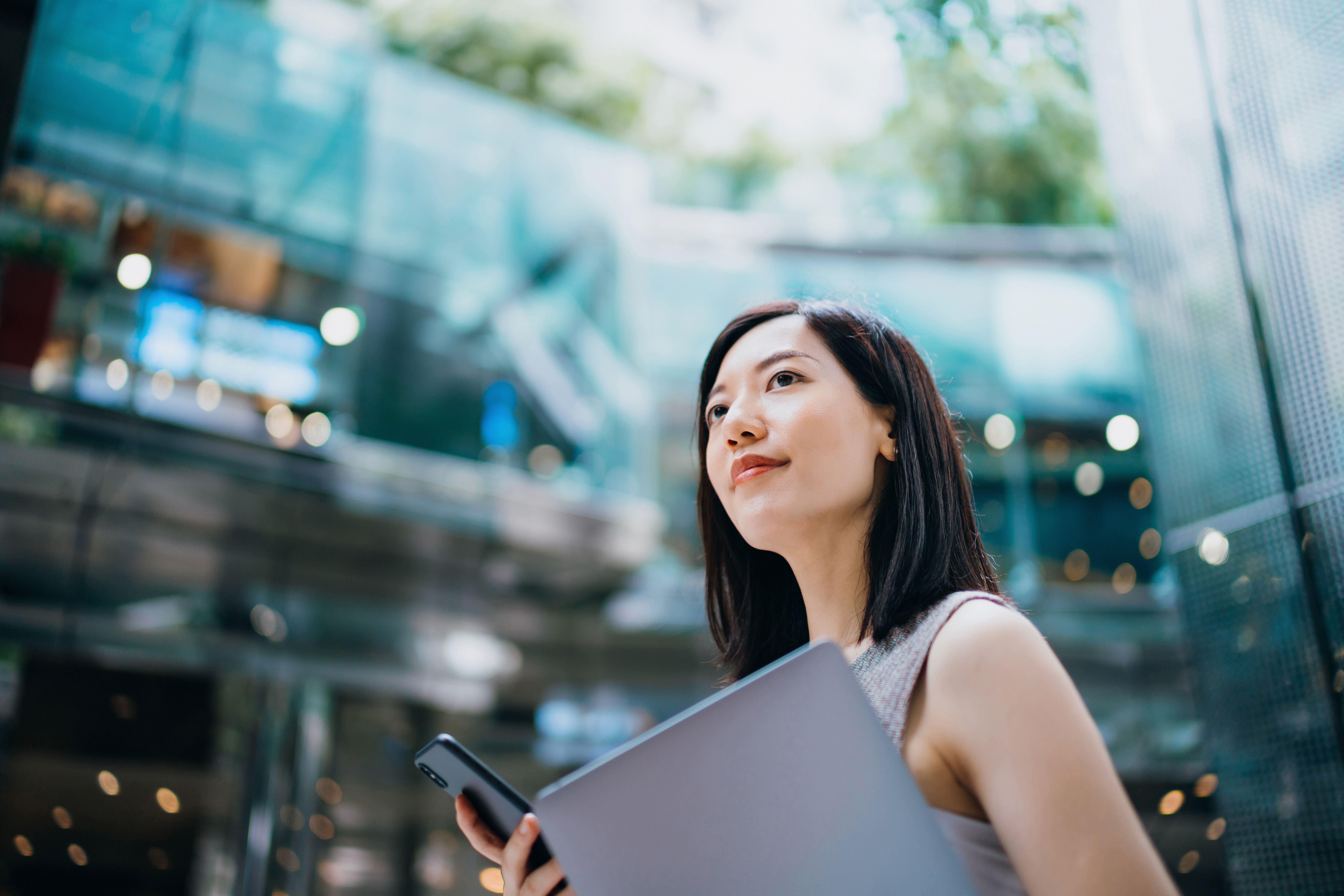 Woman looking up holding a laptop and a phone