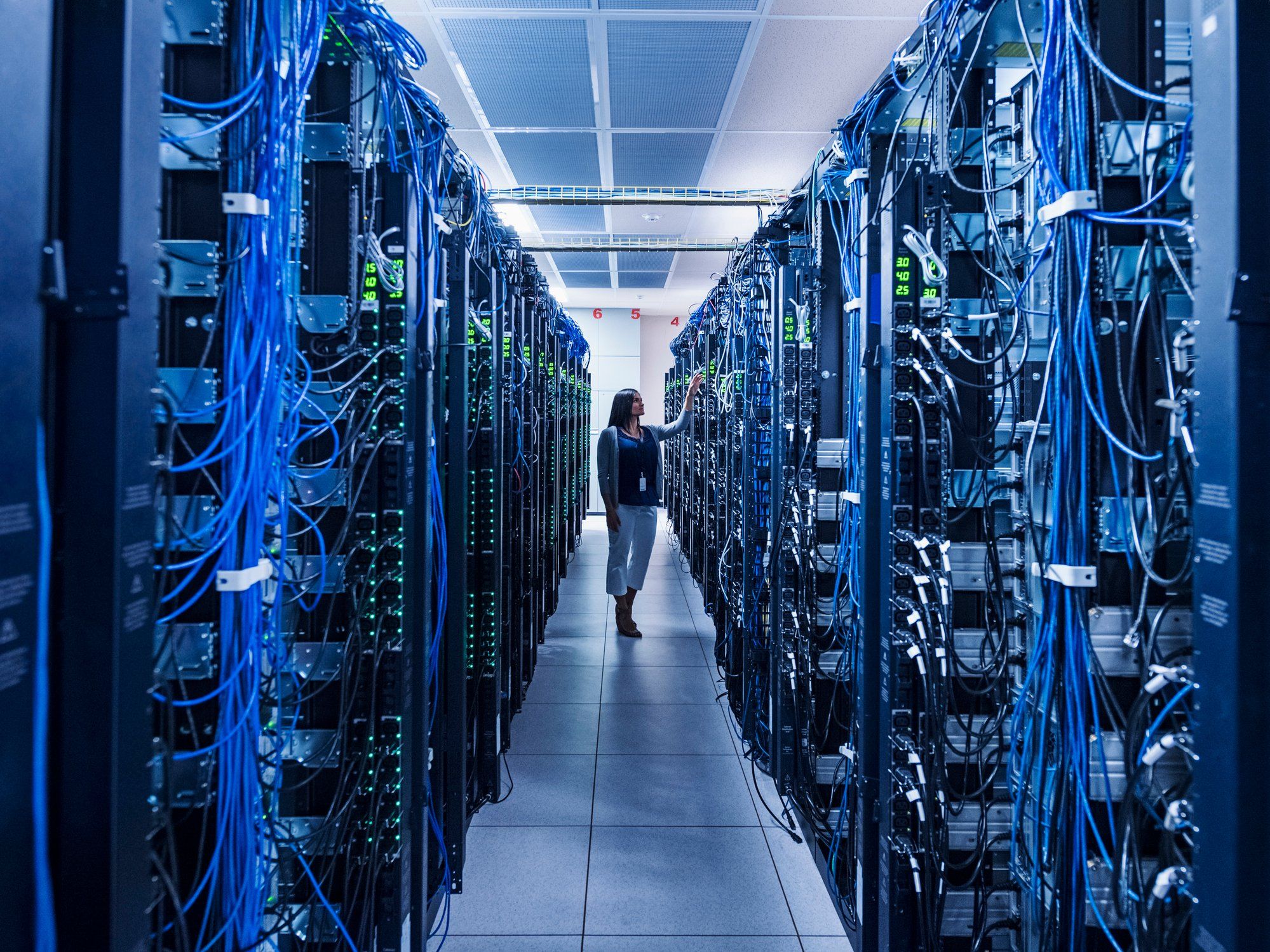 IT professional walking along a row of servers in a data center