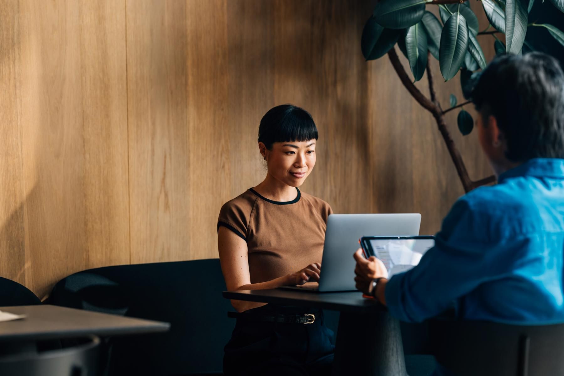 A woman sitting in a chair on a smartphone in a green office environment 