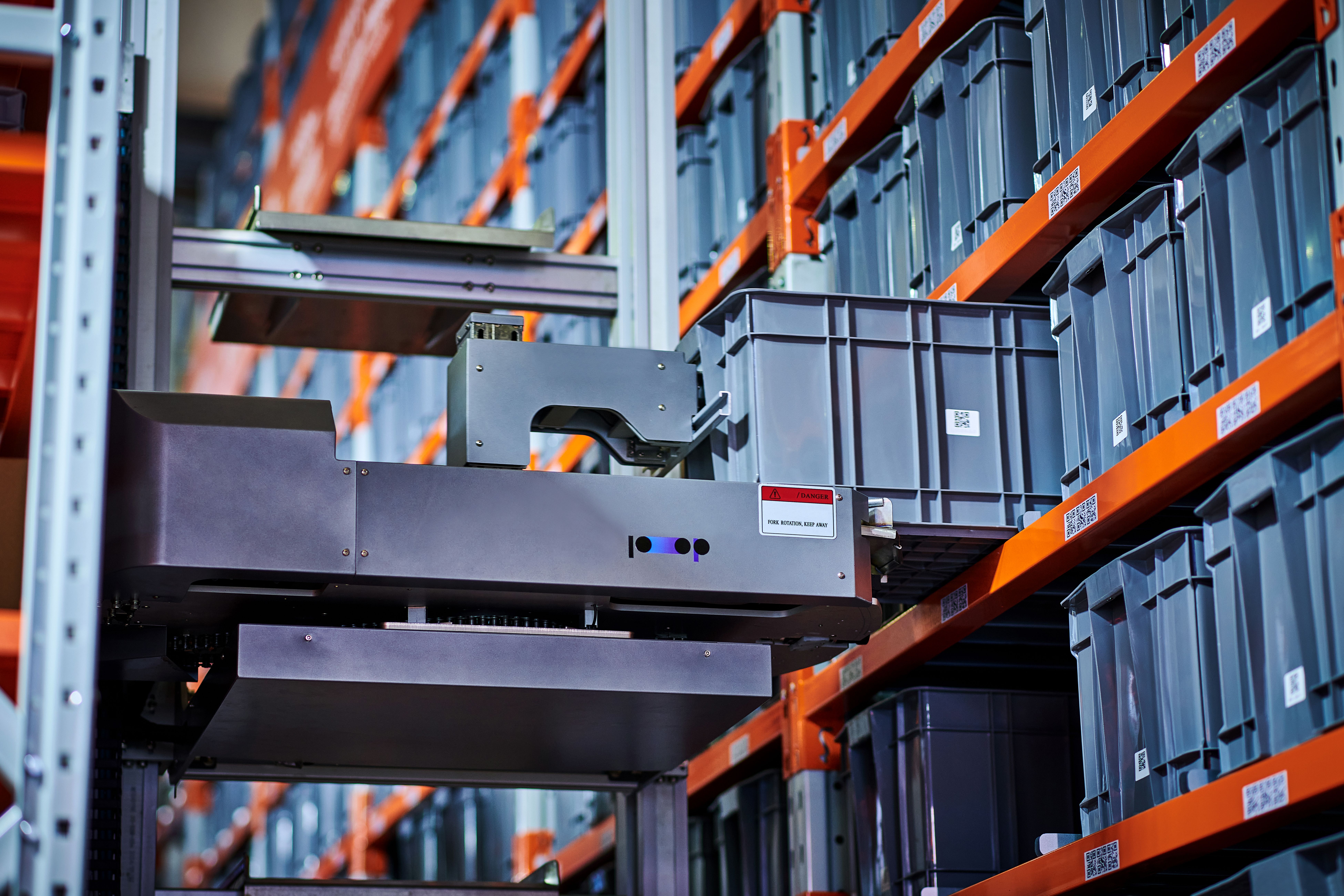 An AMR (Autonomous guided vehicle) picking a backet off a warehouse rack.