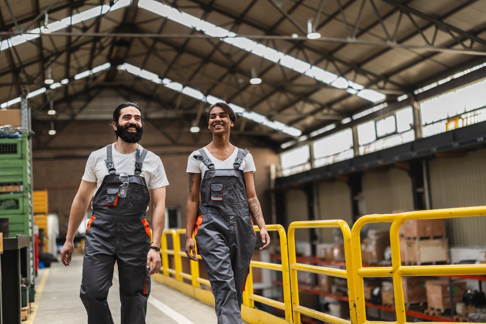 Two workers in matching work uniforms walking through a warehouse