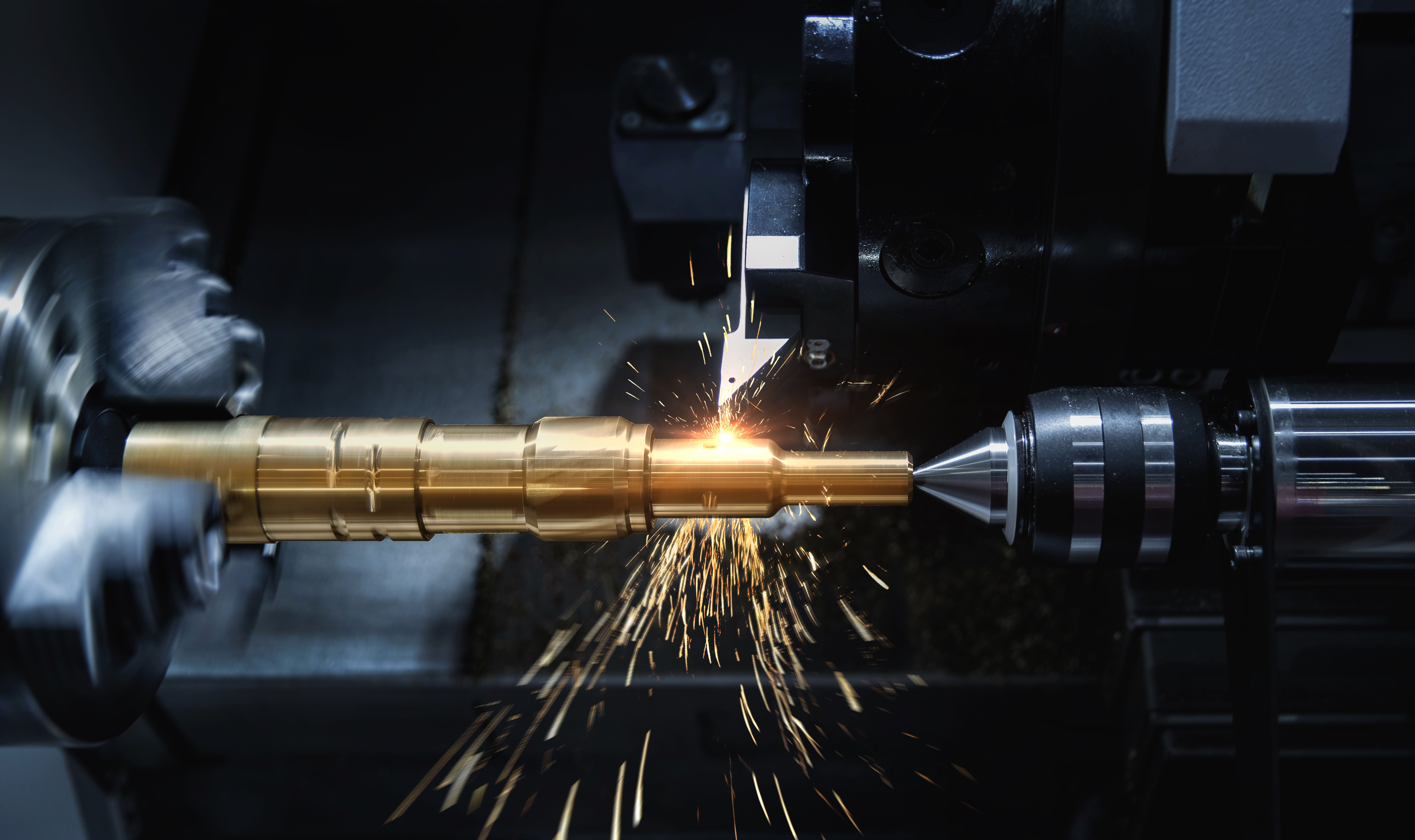 CNC lathe machining a brass part with sparks flying
