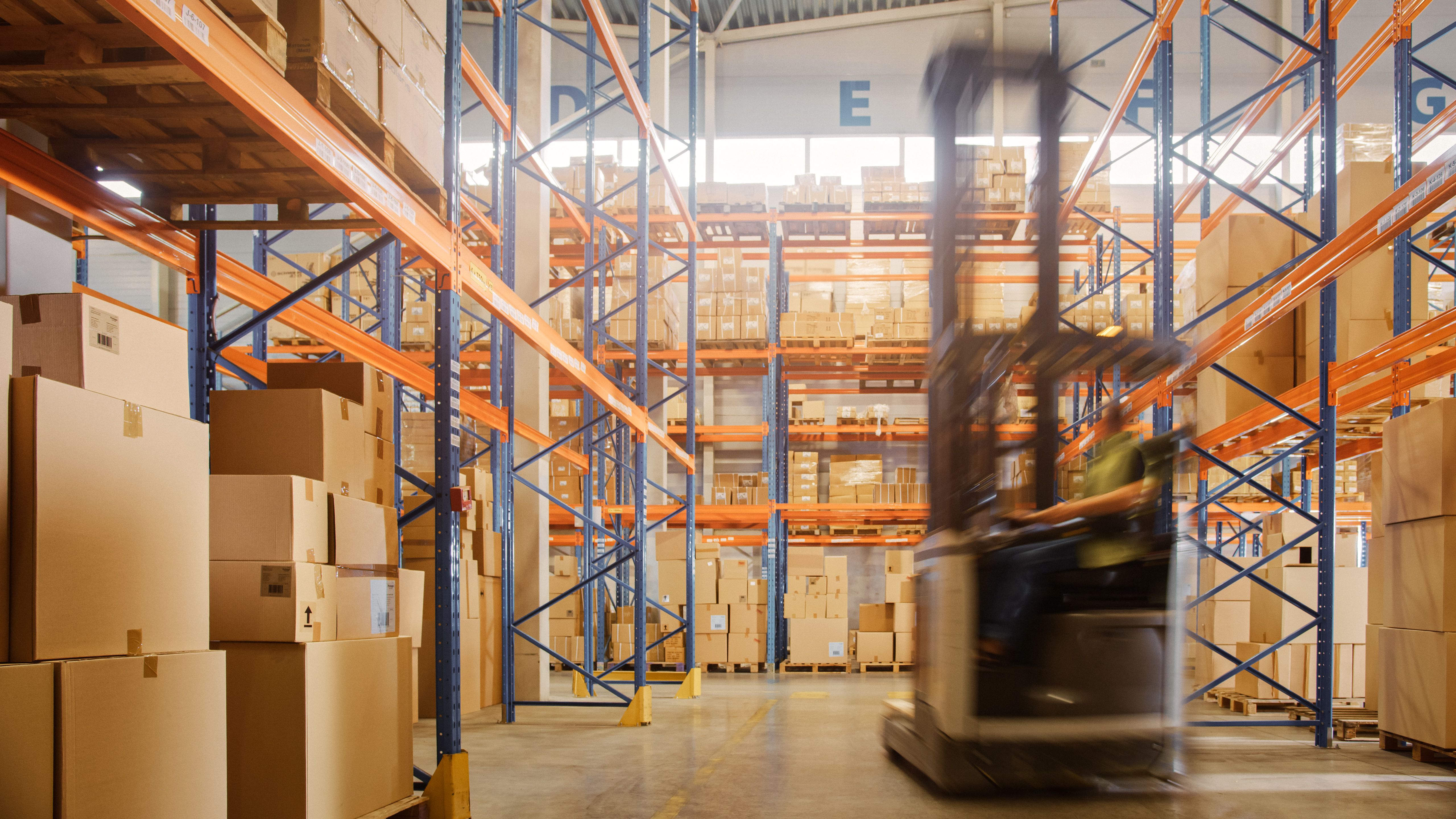 Forklift moving pallets down an aisle in a racked warehouse