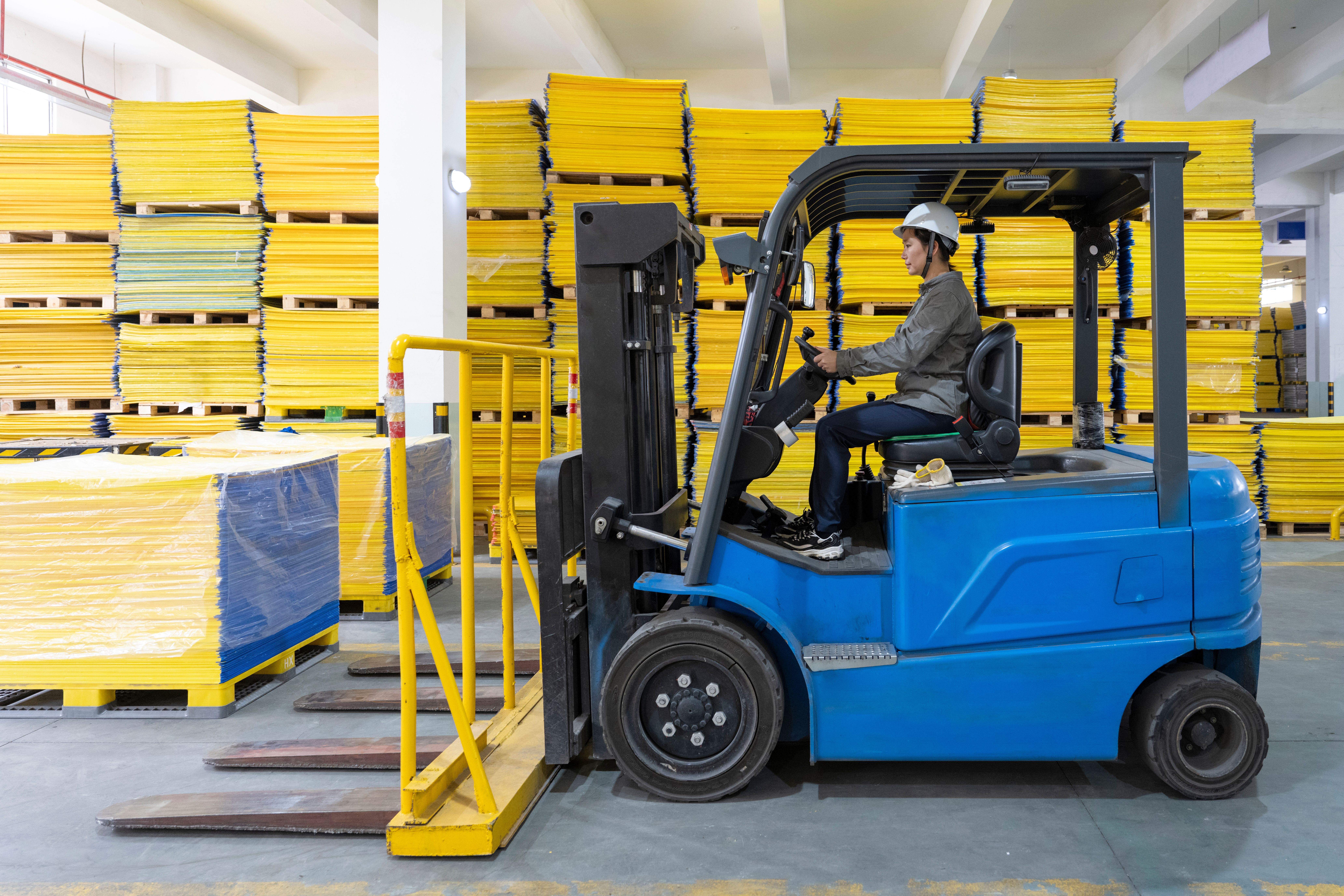 Close up of a single forklift in a warehouse with a woman operating it