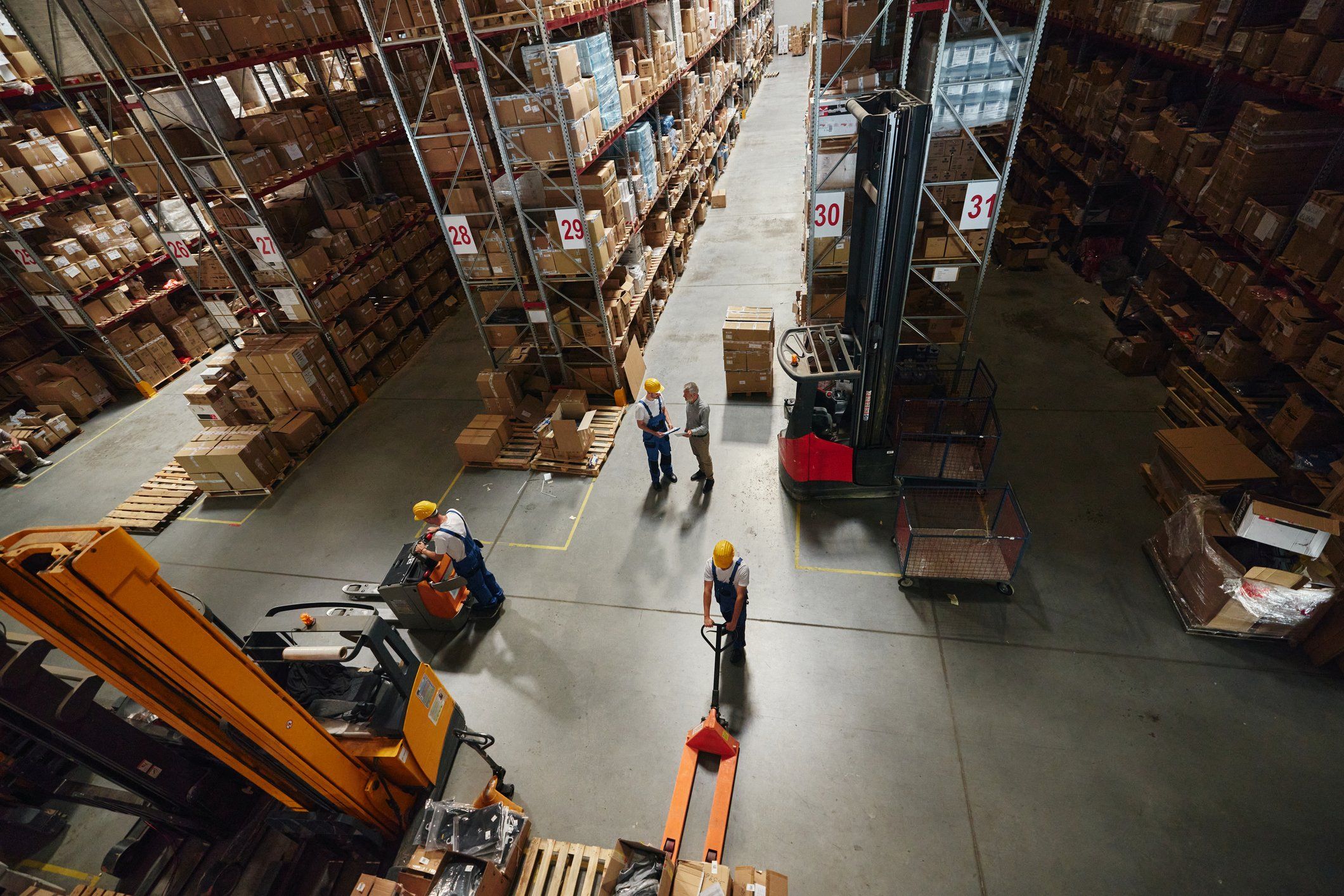 Group of people working on a modern warehouse setting with forklifts nearby