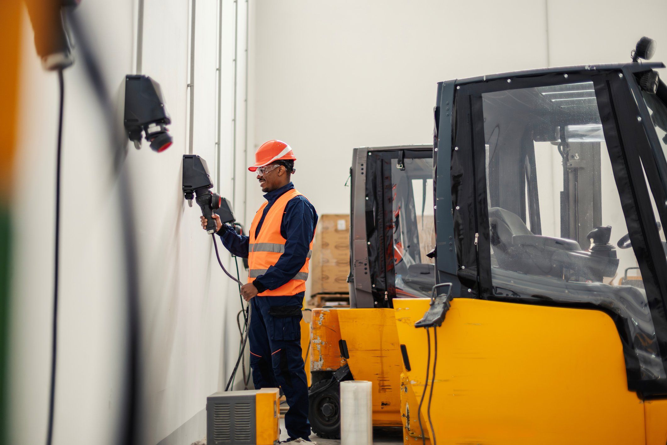 Warehouse worker plugging in an electric forklift