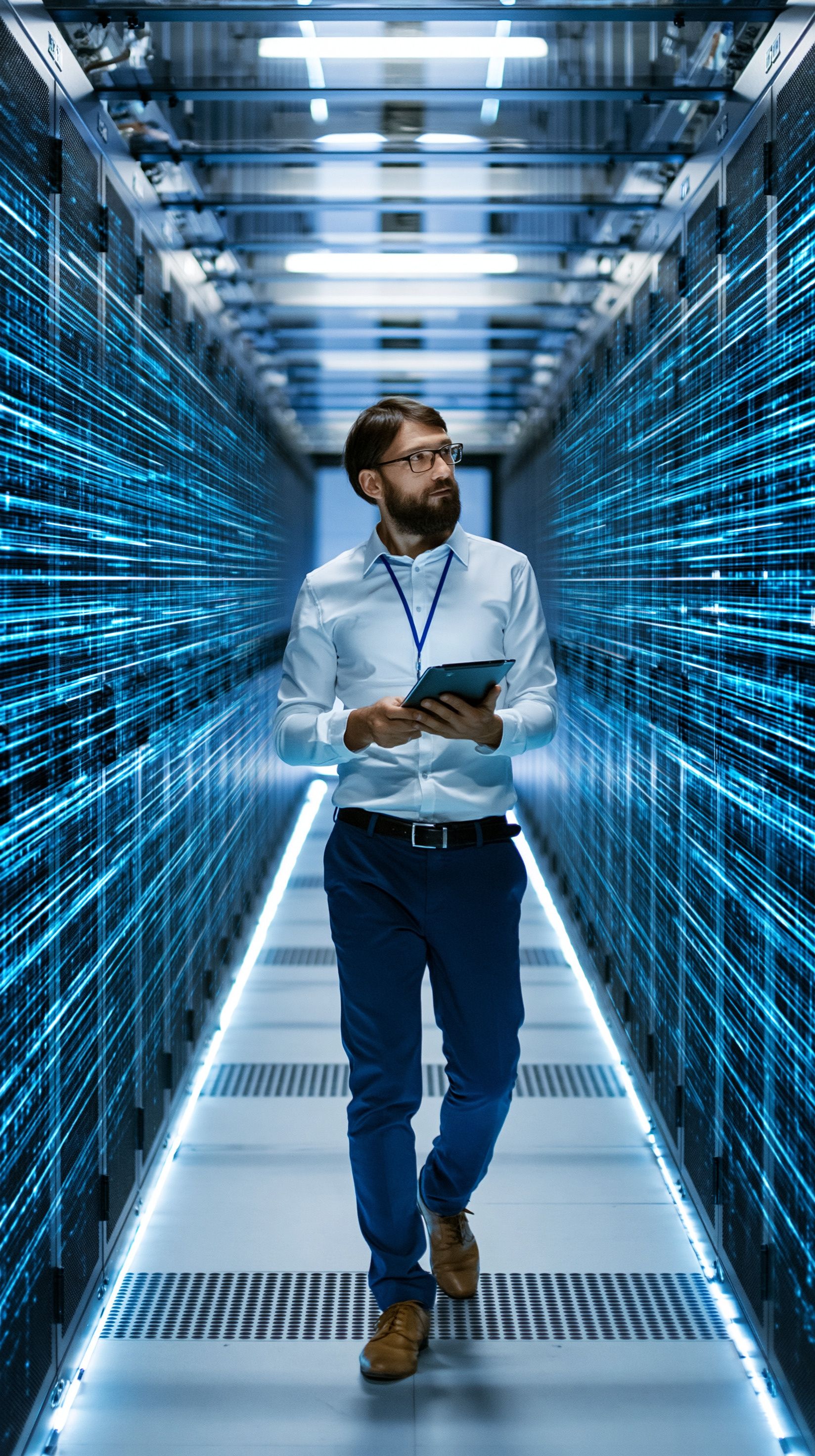 IT-Fachkraft, die in einem Rechenzentrum durch einen Gang läuft