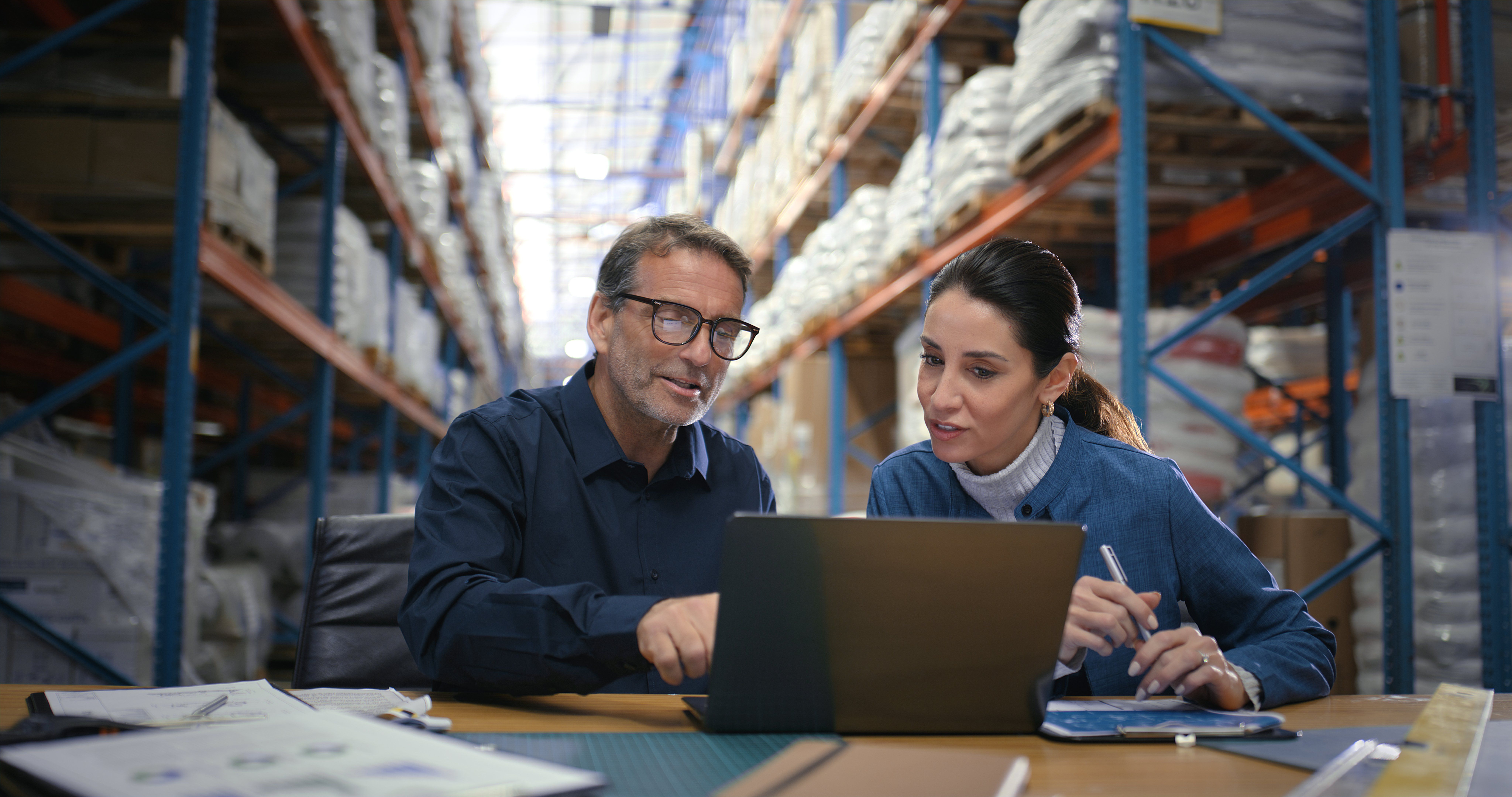 Man and woman looking at a laptop in a warehouse
