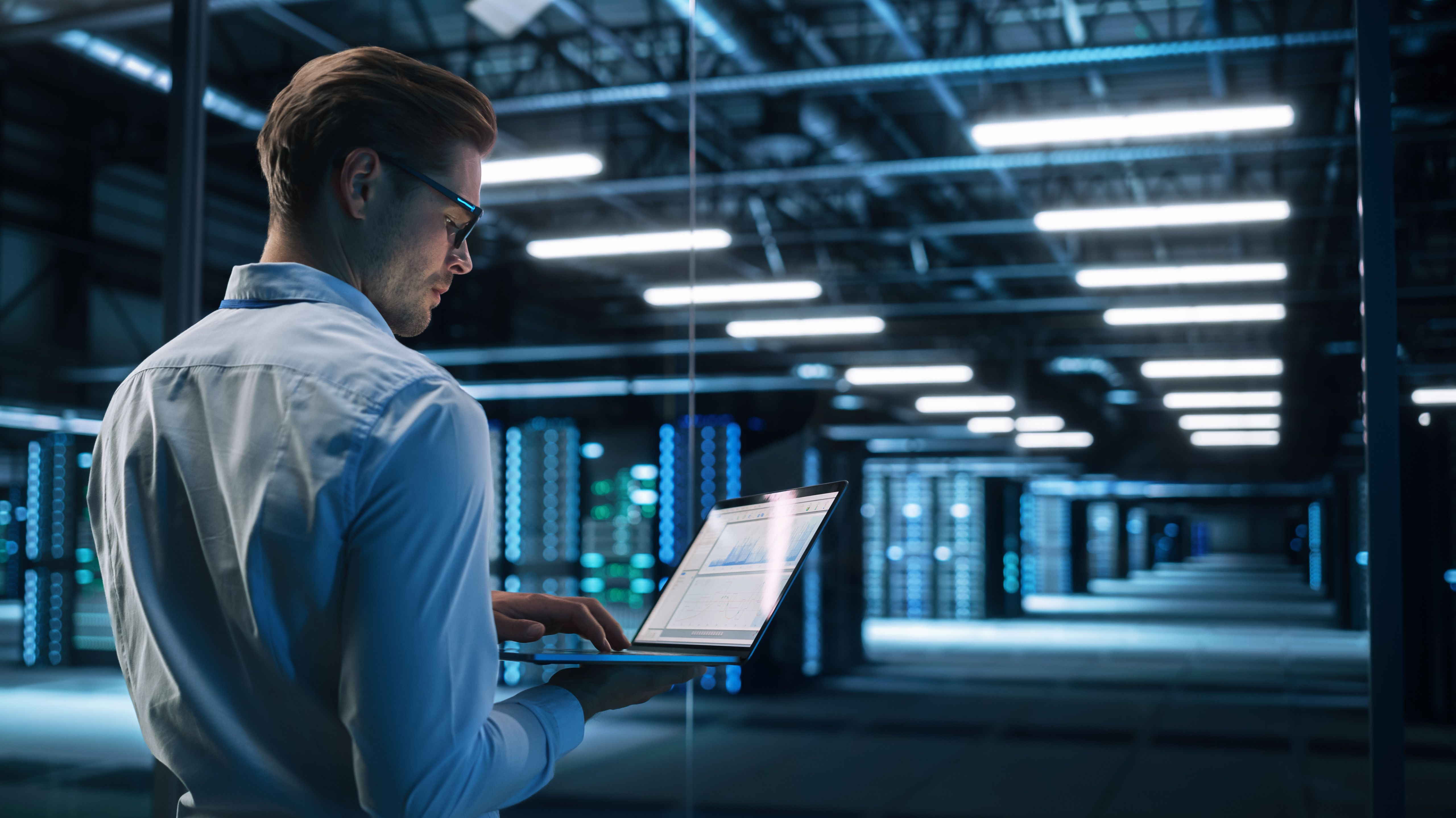 IT professional working on a laptop in a data center